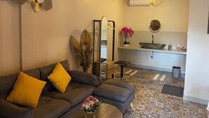 A modern living room with a grey sofa, yellow cushions, a decorative mirror, and a patterned floor. - Desa Hostel (Munduk)