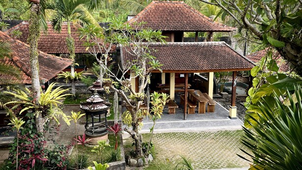 A traditional-style building with a tiled roof and wooden benches. - Desa Hostel (Munduk)