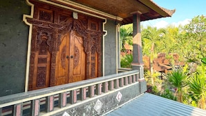 A traditional wooden building with intricate carvings on the doors and a balcony with a metal railing. - Desa Hostel (Munduk)