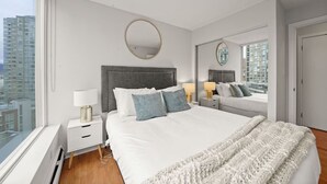 Een moderne slaapkamer met een groot bed, nachtlampjes, een spiegel en uitzicht op de stad.