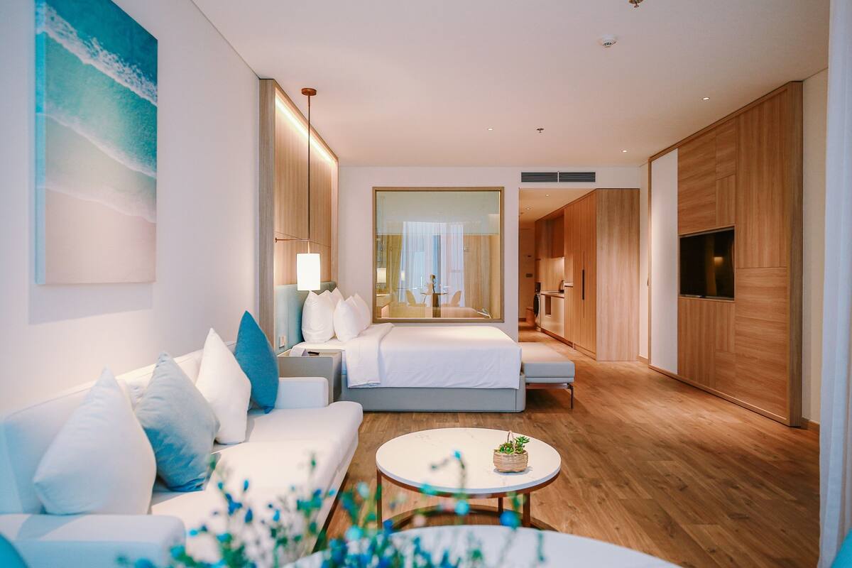 Ein modernes Hotelzimmer mit Sofa, Bett, Couchtisch und Fernseher.