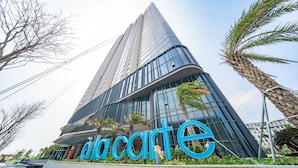 A modern building with a prominent 'Accarte' sign, featuring a glass facade and surrounded by palm trees.