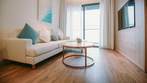 A modern living room with a white sofa, a round coffee table, and a large window with curtains.
