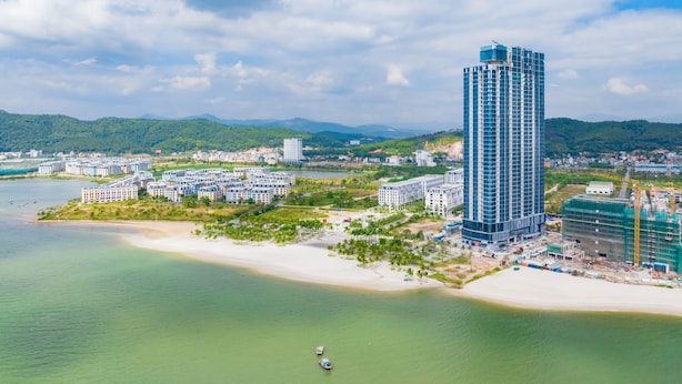 A coastal cityscape with a prominent high-rise building, residential areas, and a beach.