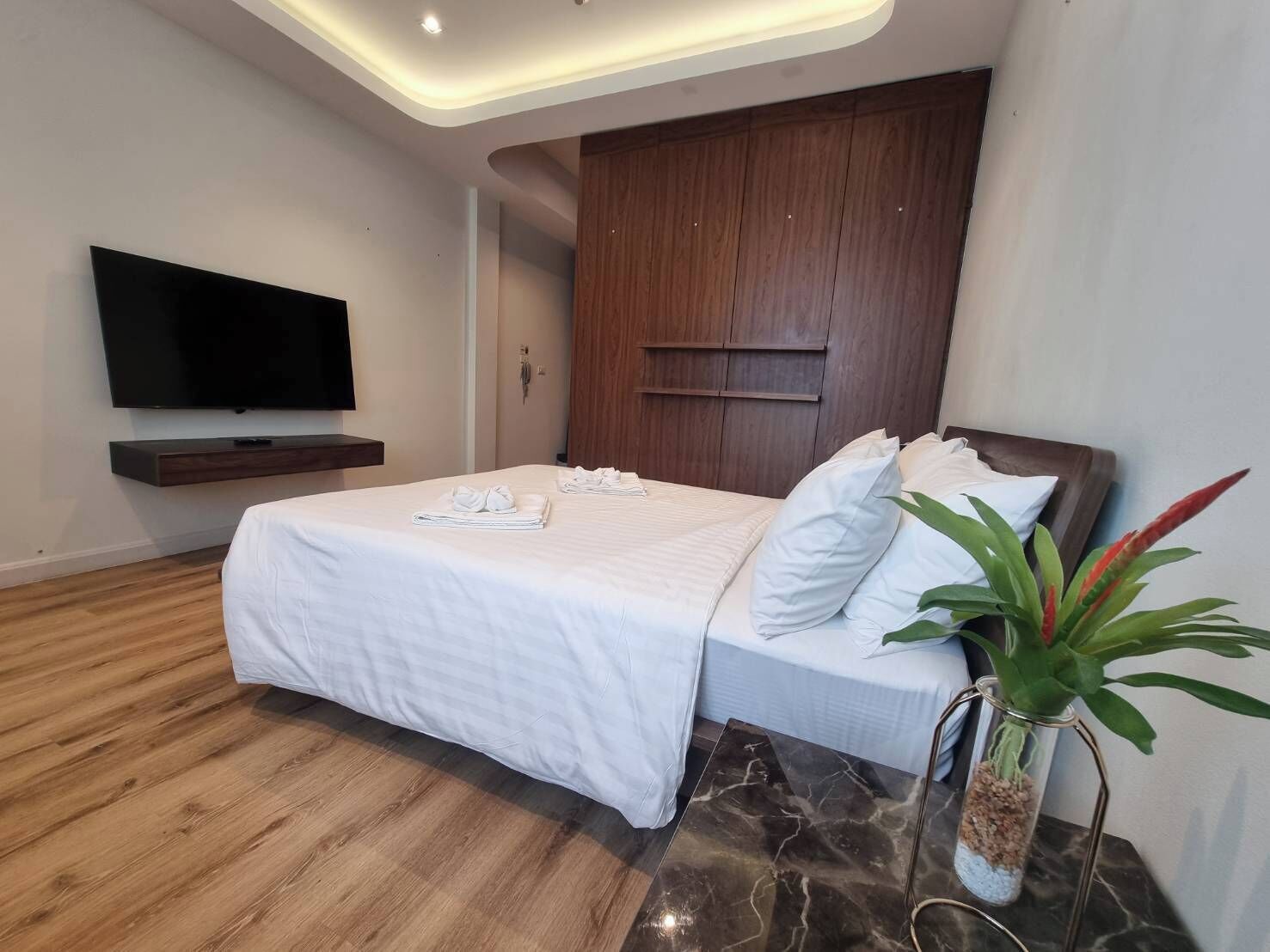 Ein modernes Hotelzimmer mit einem großen Bett, einem flachbildfernseher an der Wand und einem hölzernen Kopfteil.