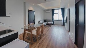 A modern kitchen with a dining area, a sofa, and a large window. - Play Poshtel & Cafe (Krabi)