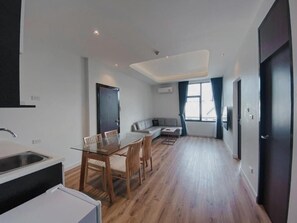 A modern kitchen with a dining area, a sofa, and a large window. - Play Poshtel & Cafe (Krabi)