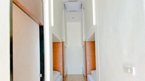 A narrow hallway with wooden flooring and white walls, leading to a room with a bed. - Play Poshtel & Cafe (Krabi)