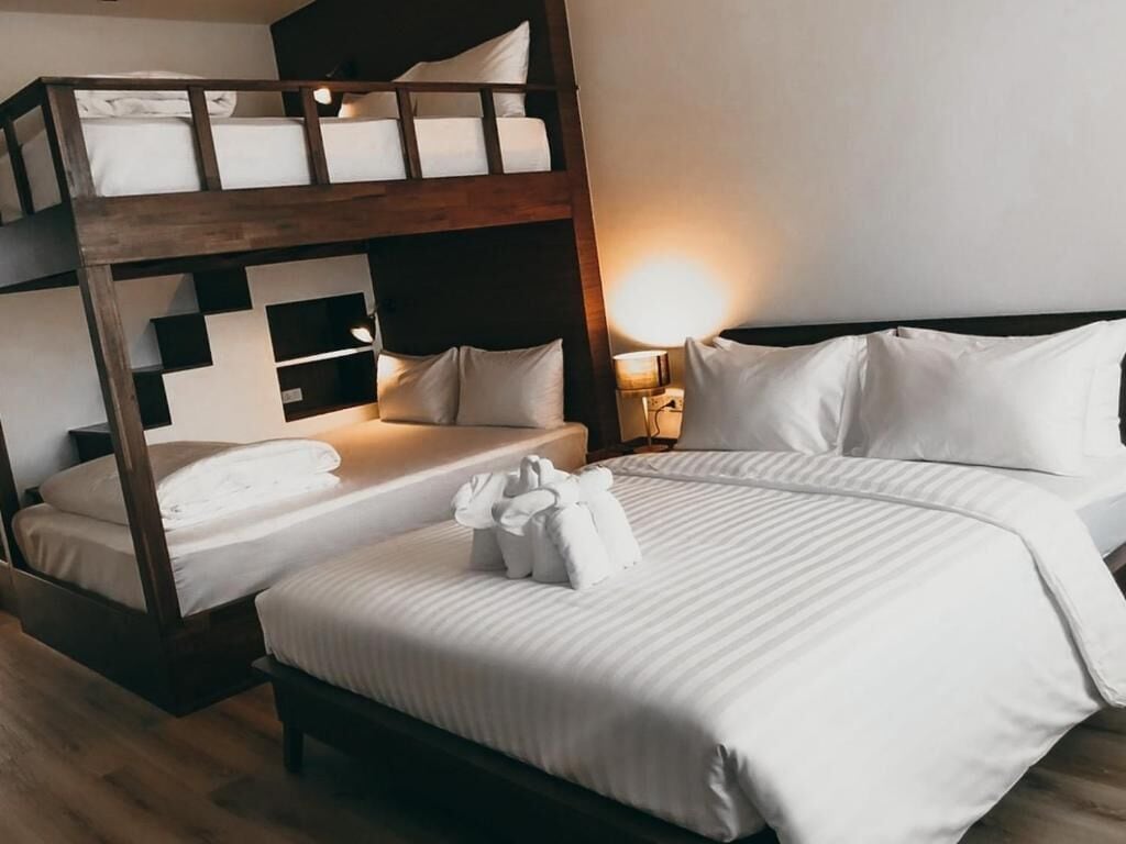 Una habitación con una cama individual, una litera y una mesita de noche con lámpara.