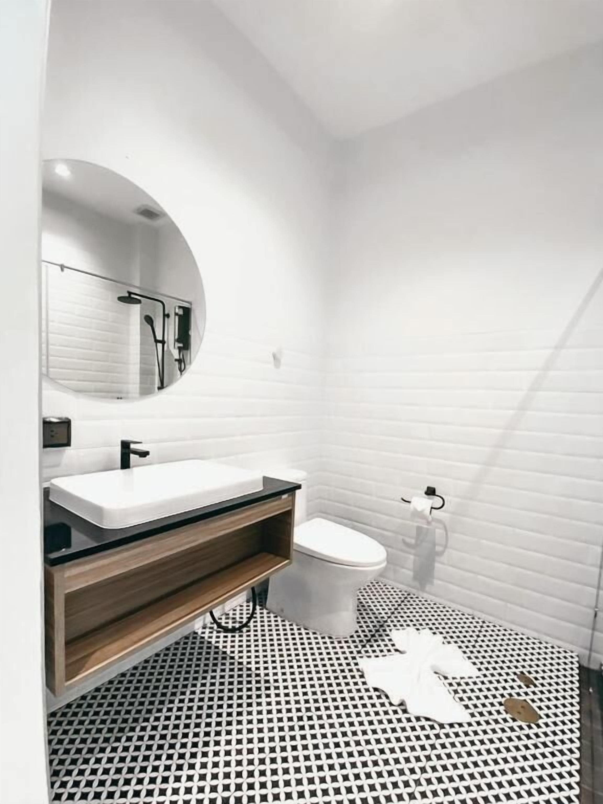 Un baño moderno con lavamanos, inodoro y ducha blancos.