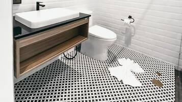 Un baño moderno con lavamanos, inodoro y ducha blancos.