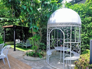 A garden with a gazebo, outdoor seating, and a decorative birdcage. - Play Poshtel & Cafe (Krabi)