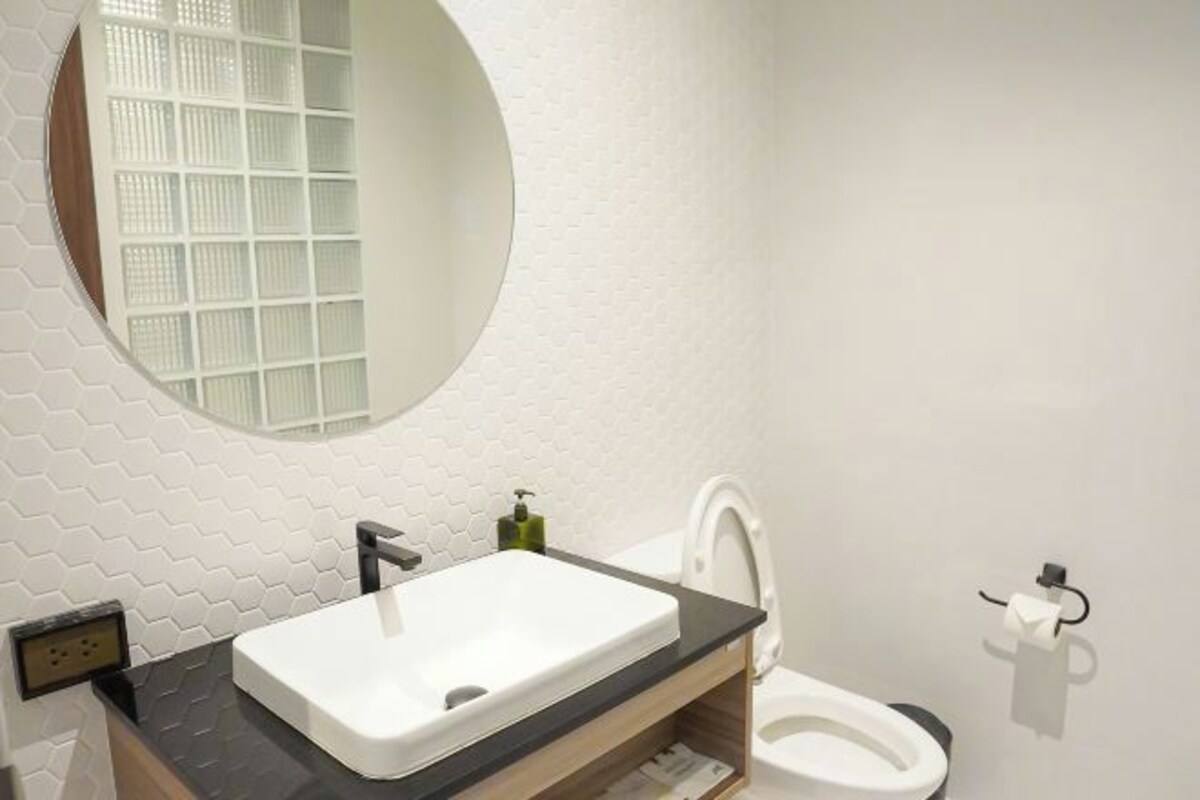 A bathroom with a white sink, a mirror, and a toilet.