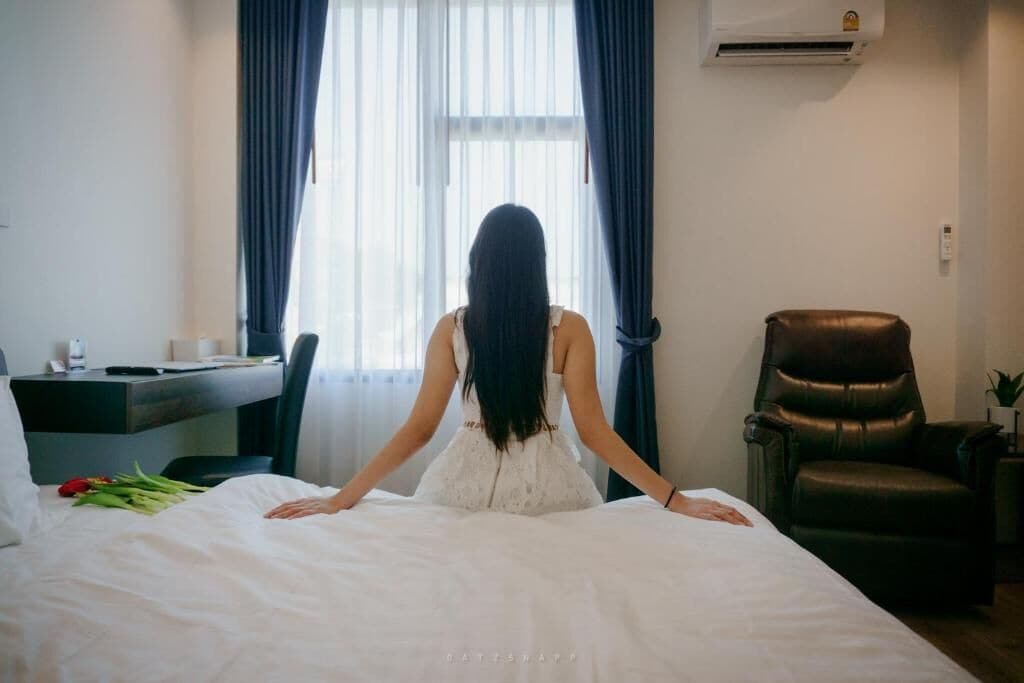 A room with a bed, a desk, a chair, and a window with curtains.