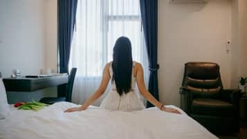 A room with a bed, a desk, a chair, and a window with curtains.