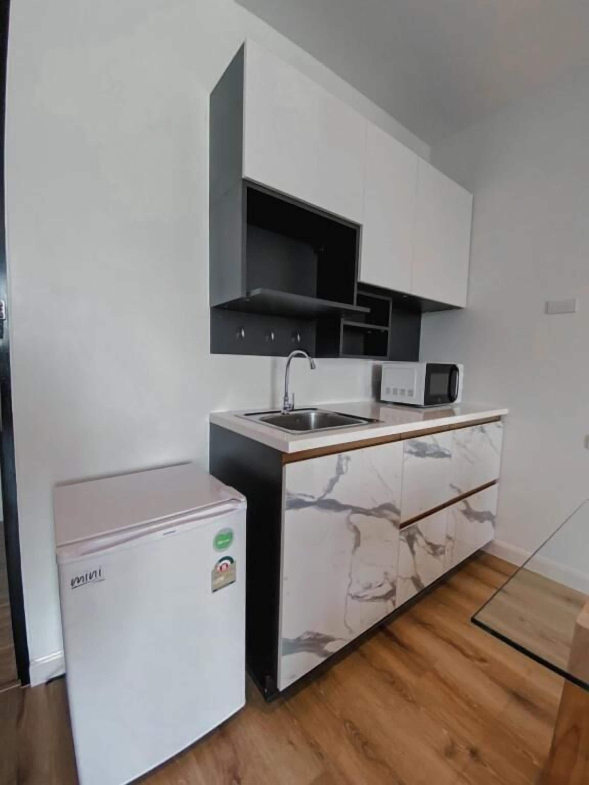 Una cocina compacta equipada con refrigerador, microondas y pileta.