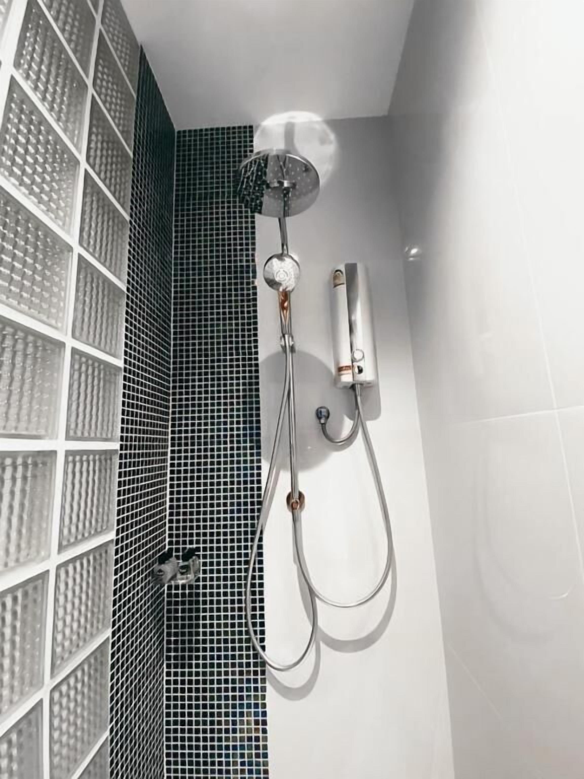 A shower with a handheld showerhead and a wall-mounted control panel.