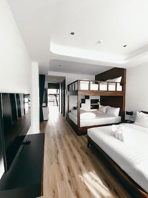 Een moderne hotelkamer met een stapelbed, een flatscreen televisie en een houten vloer.