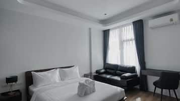 A modern hotel room with a large bed, a desk, and a chair.