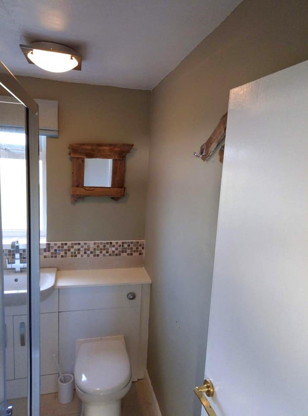 A small bathroom with a toilet, a sink, and a mirror.