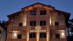 A multi-story building with a sign reading "NaturaLodge" and a logo above the entrance. - Naturae Lodge (Alleghe)