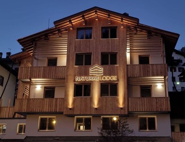 A multi-story building with a sign reading "NaturaLodge" and a logo above the entrance. - Naturae Lodge (Alleghe)