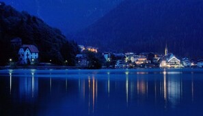A lakeside town with a church and residential buildings at dusk. - Naturae Lodge (Alleghe)