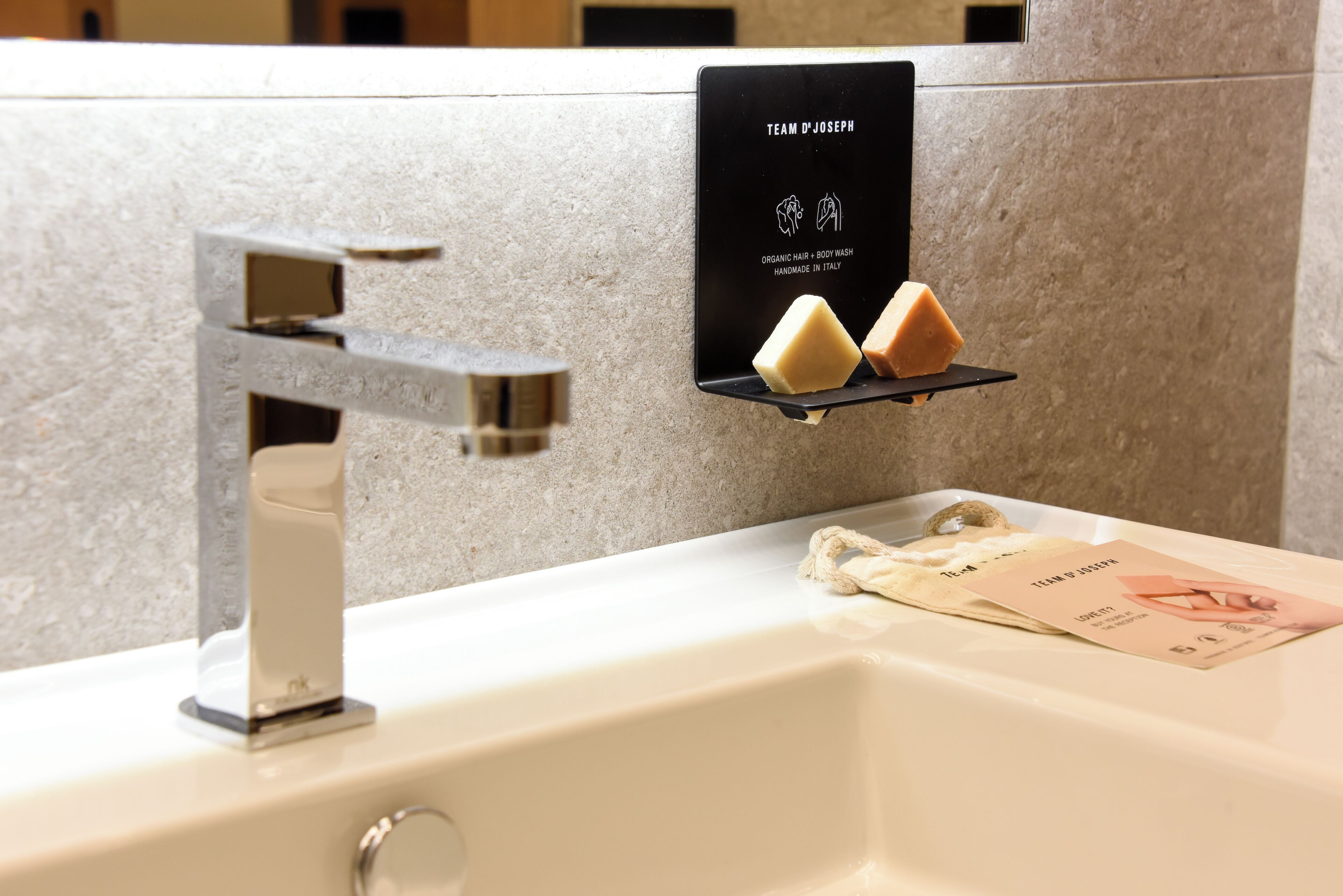 Une salle de bain avec un lavabo blanc, un distributeur de savon et une serviette suspendue à un porte-serviettes.