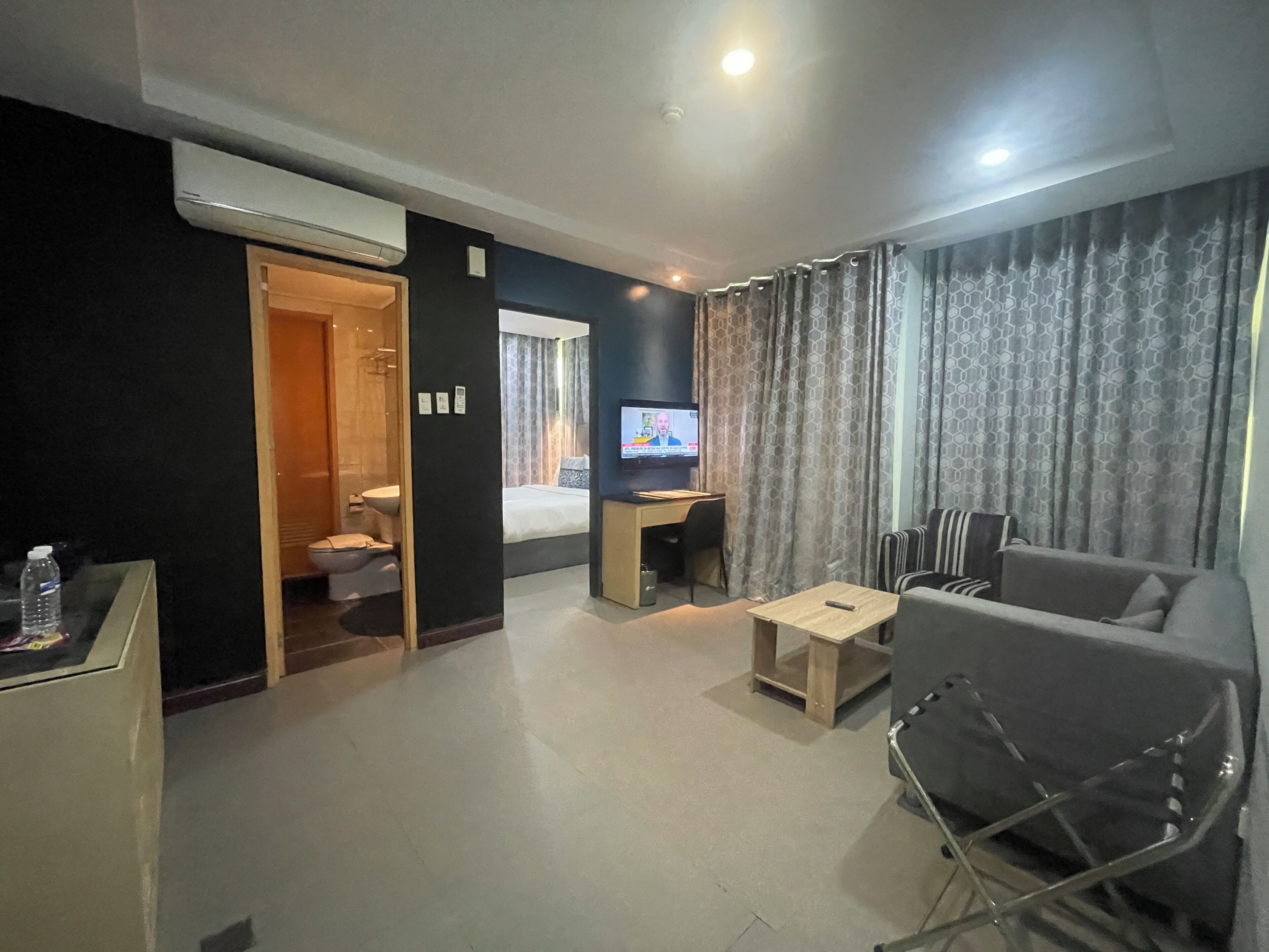 Una habitación de hotel con cama, escritorio, televisor, sofá y sillón.