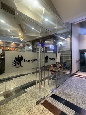 A modern hotel lobby with glass partitions, a reception desk, and a chandelier. - Homes at Bay Area Suites by SMS Hospitality (Manila)