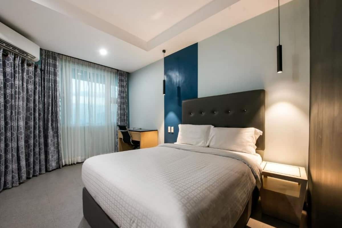 A hotel room with a large bed, a desk, and a chair.