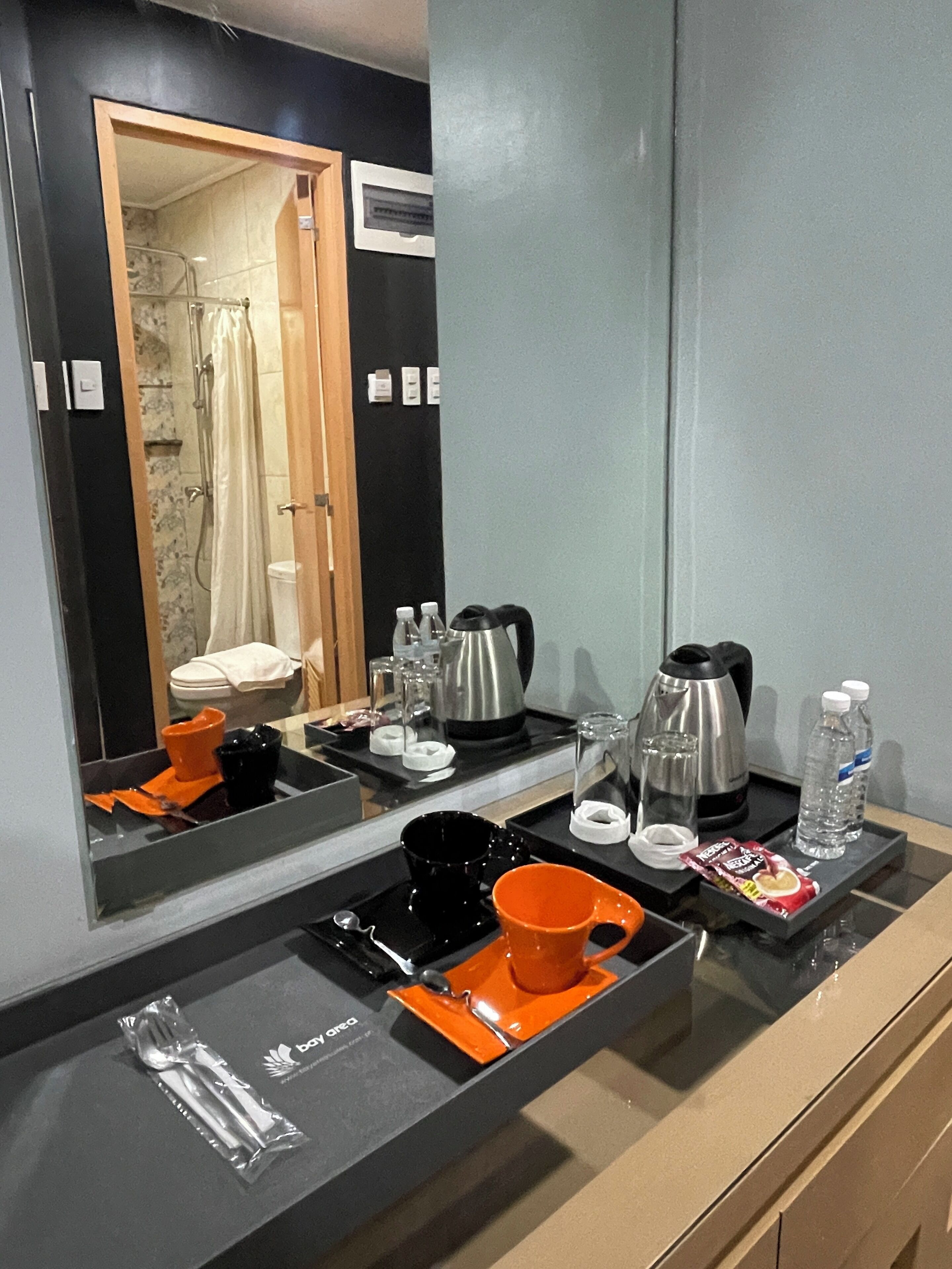 Ein Badezimmer in einem Hotel mit Spiegel, Pflegeprodukten, einer Dusche und einem Waschbecken.