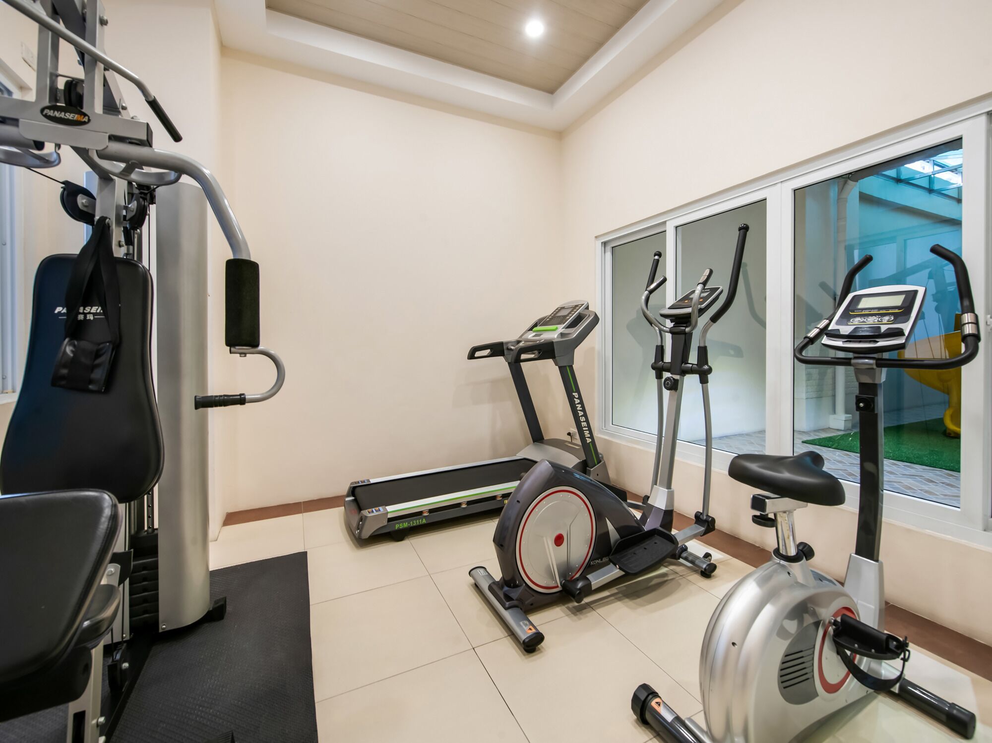 Un gimnasio con equipo de ejercicio que incluye una caminadora, elíptica y máquina de pesas.