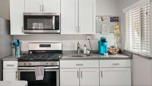 Une cuisine moderne avec des armoires blanches, un four à micro-ondes encastré, une cuisinière et un évier.