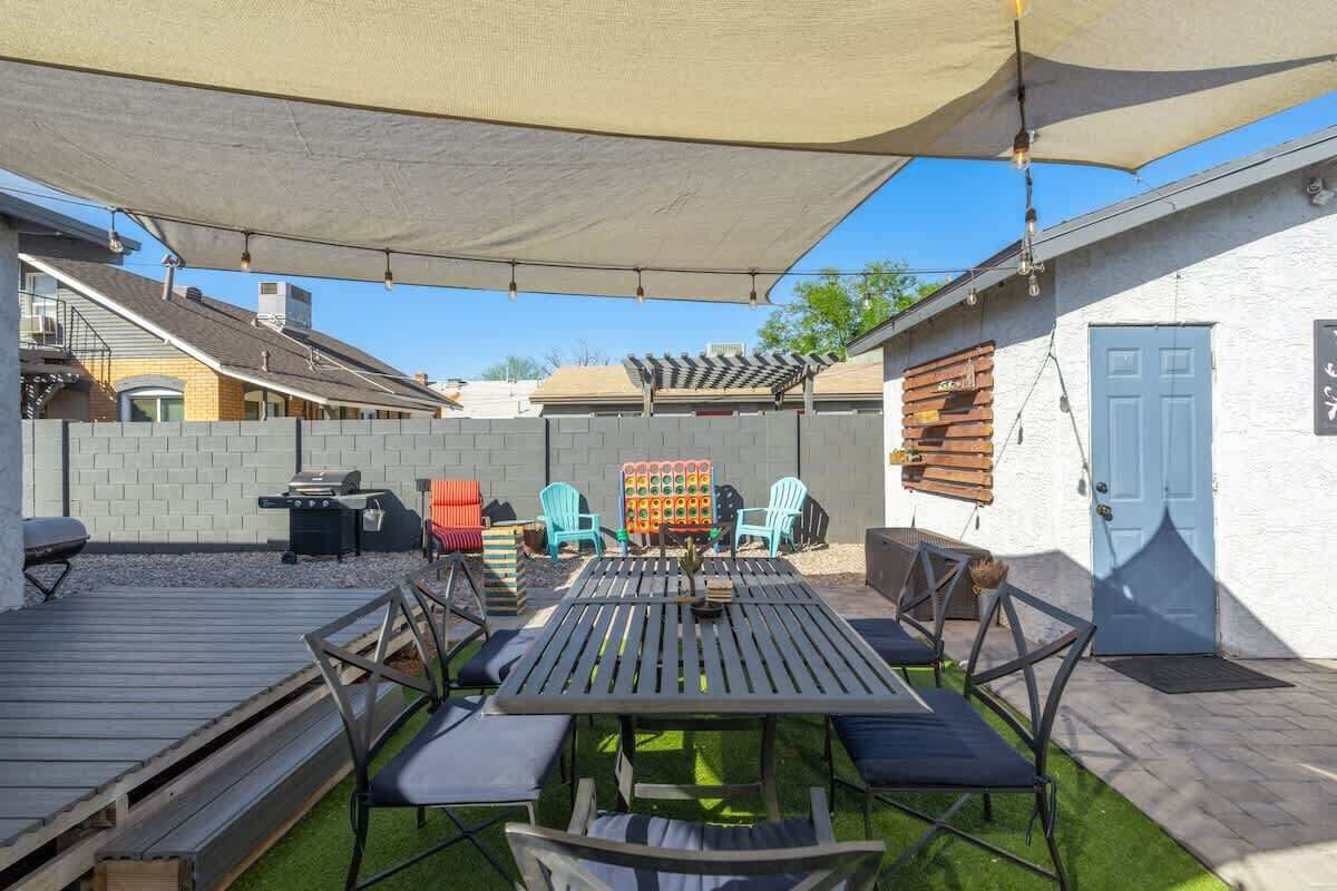 Eine Terrasse im Freien mit Tisch, Stühlen, einem Grill und einem schattigen Bereich.
