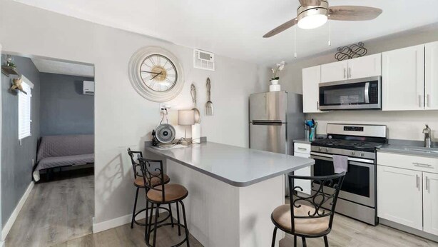 Une cuisine de taille réduite avec un îlot central, un ventilateur de plafond et un four à micro-ondes.