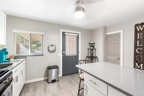 A modern kitchen with a grey door, a welcome sign, and a trash bin. - Central Phoenix Casita w/ Beautiful Patio (Unit B) (Phoenix)