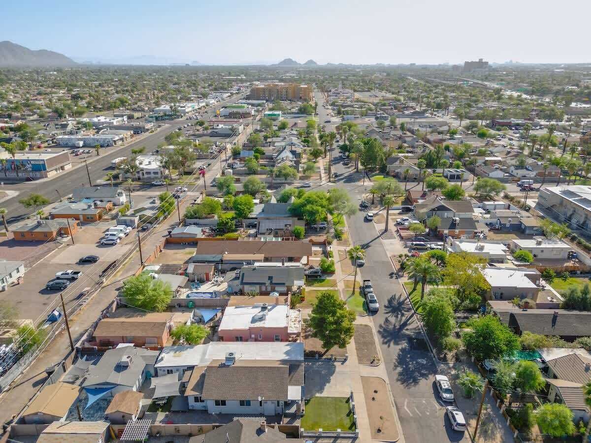 An aerial view of a residential area with houses, streets, and a distant mountain range.