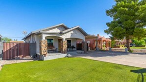 A residential property with a well-maintained lawn, a stone foundation, and a gated entrance.