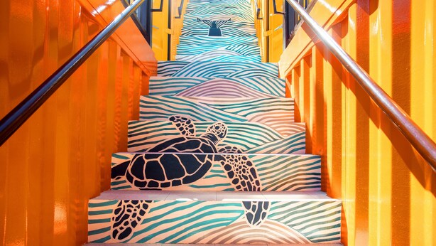 Una escalera con un diseño de tortuga en los peldaños y un patrón de olas en las paredes.