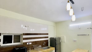 A modern kitchen with a granite countertop, a built-in microwave, a refrigerator, and a window above the sink. - Chaubey Farms- Relax & Rejoice
- The best farm stay in Hyderabad (Chilipched)