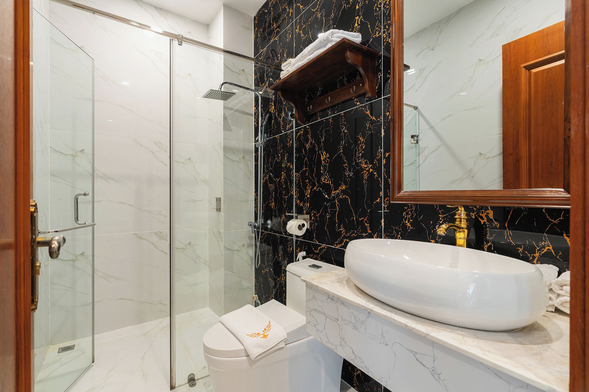 A bathroom with a glass-enclosed shower, a toilet, a sink with a marble countertop, and a wooden medicine cabinet.