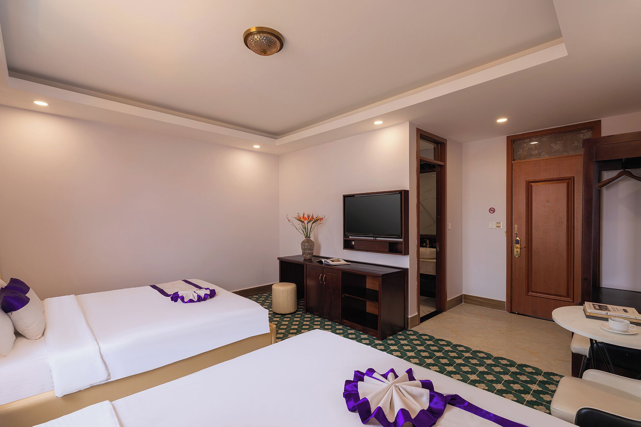 A hotel room with two beds, a television, a desk, and a small table.