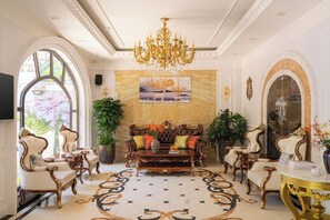 A grand room with a large sofa, ornate chairs, a chandelier, and a large painting on the wall. - Peach Valley (Xuan Huong - Da Lat)