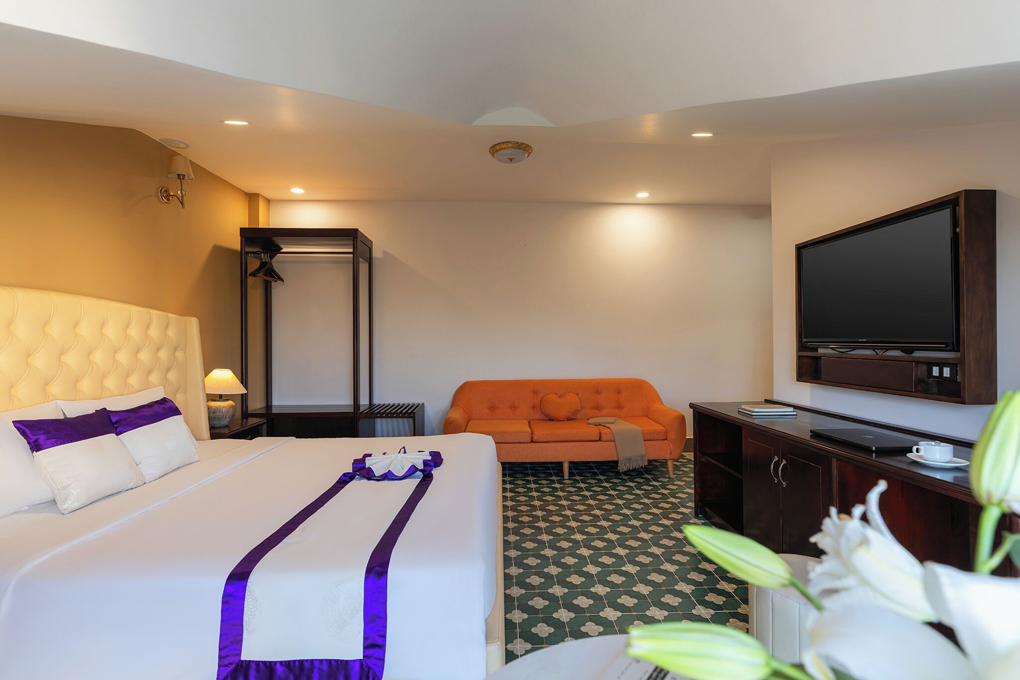 A hotel room with a bed, a sofa, a television, and a desk.