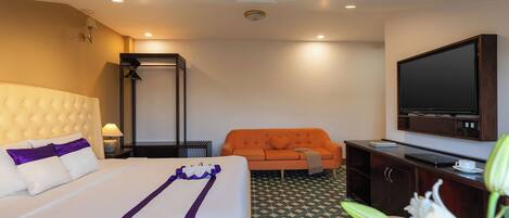 A hotel room with a bed, a sofa, a television, and a desk.
