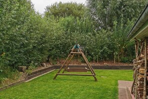 Relax in a serene outdoor space surrounded by lush greenery and a wooden swing set.