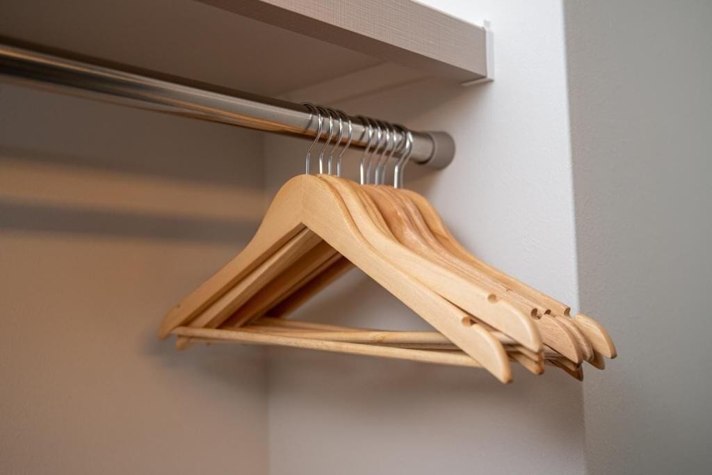 A wooden hanger rack with multiple hangers against a wall.