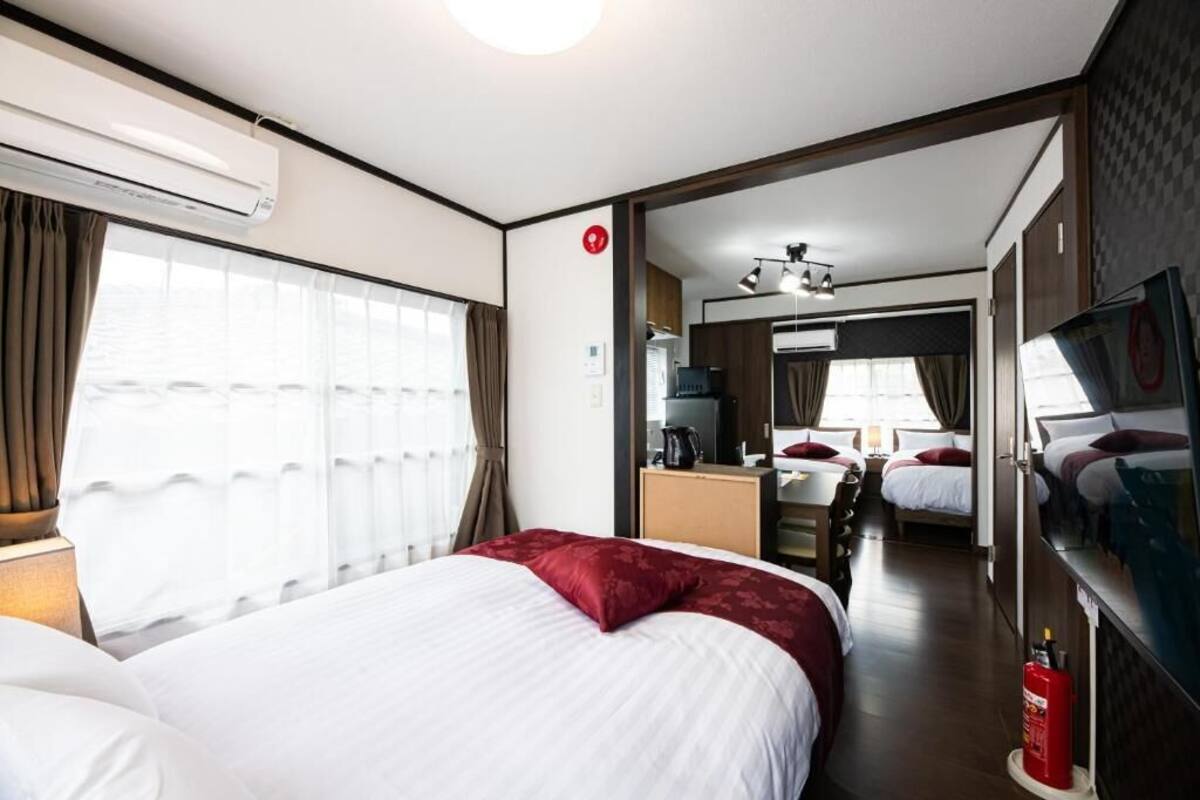 A hotel room with a bed, a desk, a chair, a television, and a fire extinguisher.