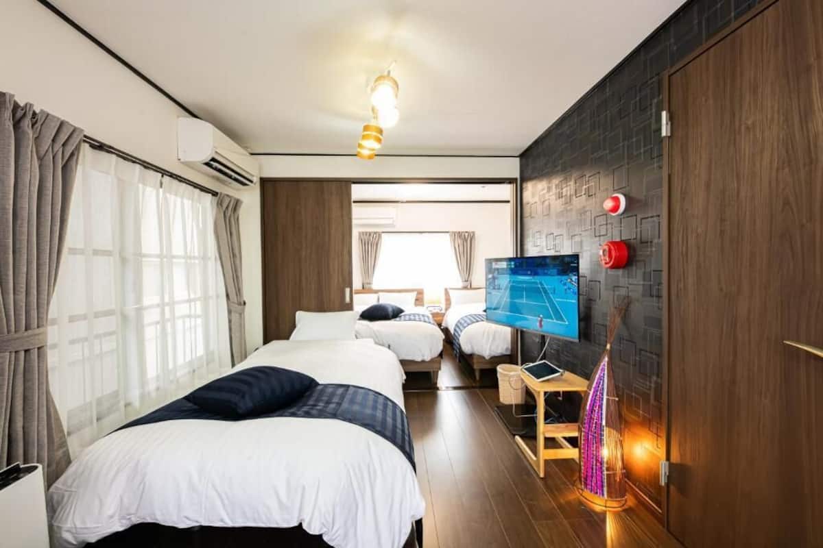 A hotel room with two beds, a TV, a wall-mounted heater, and a wooden door.